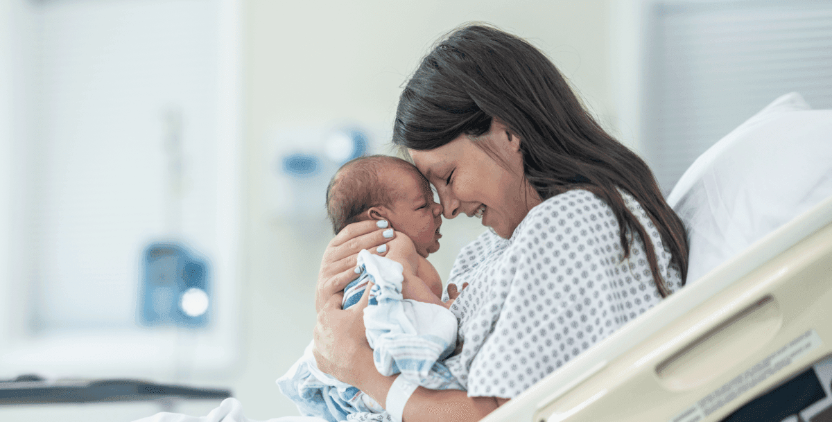 A mother holding her newborn in a hospital bed